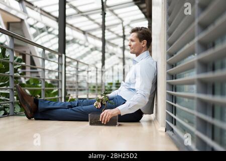 Uomo d'affari in un atrio verde, seduto in galleria Foto Stock