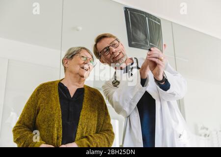 Medico che discute l'immagine radiografica della mano rotta con il paziente anziano Foto Stock