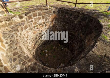 Un buco o buca a Fort Rodney risalente al periodo coloniale con lati e base coperti in pietra muratura e la parte superiore circondata da una barriera ringhiera in legno Foto Stock