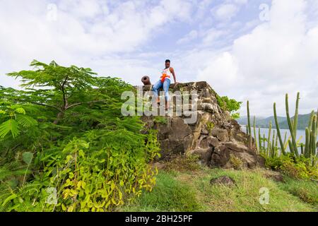 Una femmina seduta in cima alla fortezza, forte Rodney circondato da alberi verdi vicino a un cannone Foto Stock