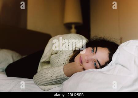 Ritratto di ragazza pusiva che si trova sul letto guardando a distanza Foto Stock