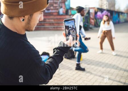 Giovani ballerini che provano in un parco di skate, facendo un video Foto Stock