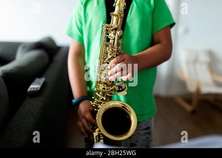 Ragazzo che si allena per giocare il sassofono a casa Foto Stock