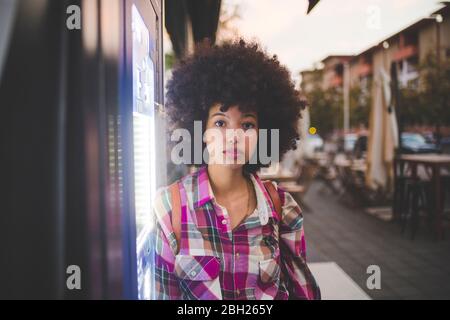 Ritratto di giovane donna con afro hairdo in città al tramonto Foto Stock