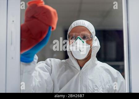 Personale addetto alla pulizia che desinfetta l'ospedale da virus scandalosi, indossando indumenti protettivi Foto Stock