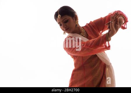 La graziosa ballerina Kathak offre un'esibizione affascinante di fronte a uno sfondo bianco. Foto Stock