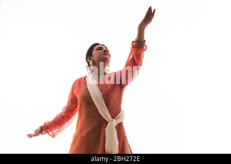 La graziosa ballerina Kathak offre un'esibizione affascinante di fronte a uno sfondo bianco. Foto Stock