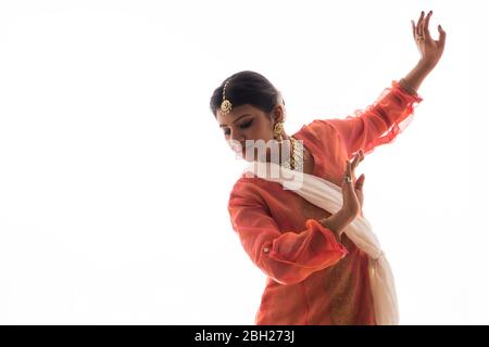 La graziosa ballerina Kathak offre un'esibizione affascinante di fronte a uno sfondo bianco. Foto Stock