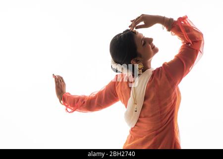 La graziosa ballerina Kathak offre un'esibizione affascinante di fronte a uno sfondo bianco. Foto Stock