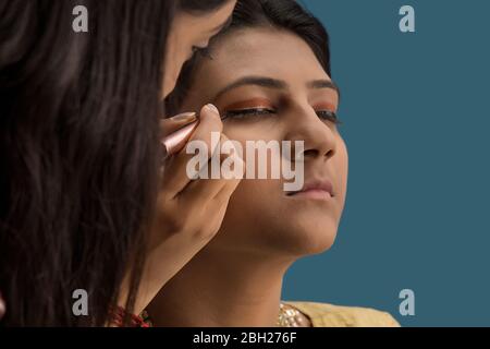 Make artist che mette eyeliner sull'occhio della ballerina di kathak. Foto Stock
