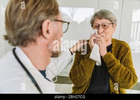 Medico confortante triste paziente anziano nella pratica medica Foto Stock