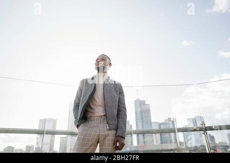 Uomo elegante in piedi sulla terrazza di osservazione con vista dello skycraper, Francoforte, Germania Foto Stock