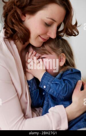 Giovane madre che conforta la sua piccola figlia Foto Stock