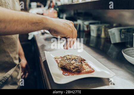 Chef che organizza il cibo sul piatto prima di servire al ristorante Foto Stock