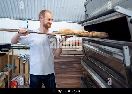 Panettiere che cuoce piccole focacce di pane in panetteria Foto Stock