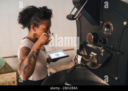 Donna che lavora in una maestria del caffè che odora il prodotto Foto Stock