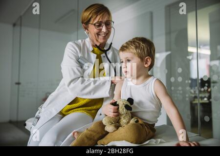 Medico che esamina il bambino con uno stetoscopio Foto Stock