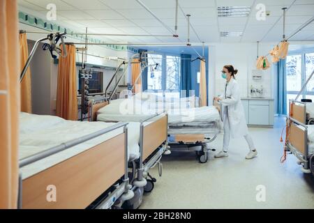 Medico in camera ospedale che spinge letti Foto Stock