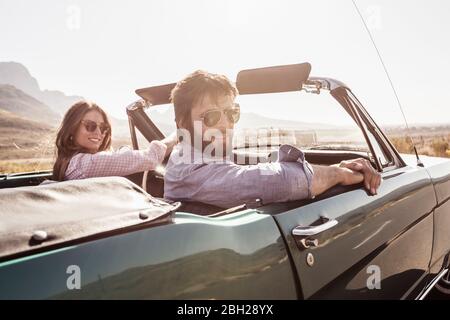 Coppia in auto convertibile in viaggio Foto Stock