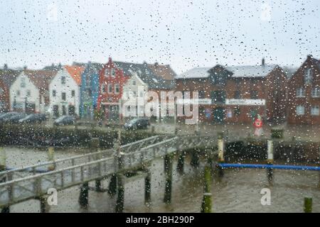 Germania, Schleswig-Holstein, Husum, Canal bridge e case sul lungomare visto attraverso finestre di vetro coperto di gocce di pioggia Foto Stock