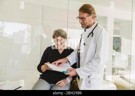 Il medico discute i risultati dei test del paziente anziano Foto Stock