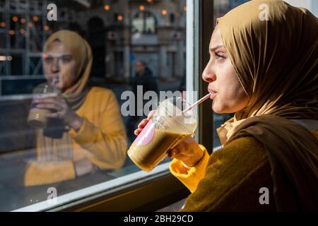 Ritratto di giovane donna che beve frullato in un caffè Foto Stock