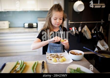 Ritratto di ragazza che peeling patate in cucina Foto Stock
