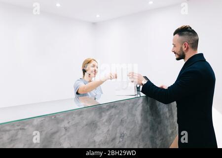 Giovane alla reception di una pratica medica che riceve una borsa Foto Stock