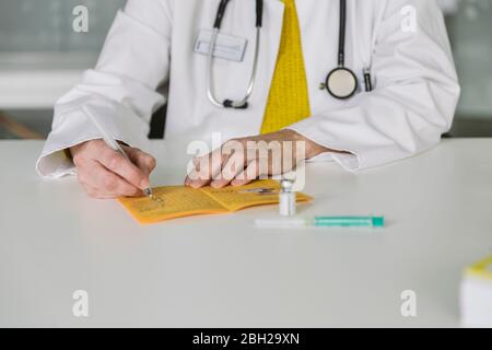 Medico che compila la scheda di immunizzazione Foto Stock