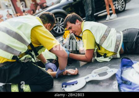 I paramedici aiutano a soccorrarsi dopo un incidente con lo scooter Foto Stock