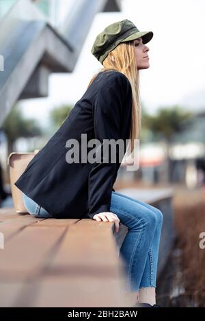 Giovane bionda che si rilassa su una panchina Foto Stock