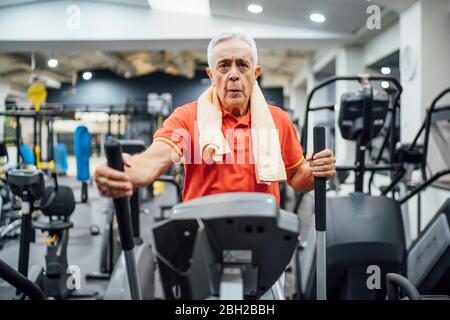 Uomo anziano che pratica allo stepper in palestra Foto Stock