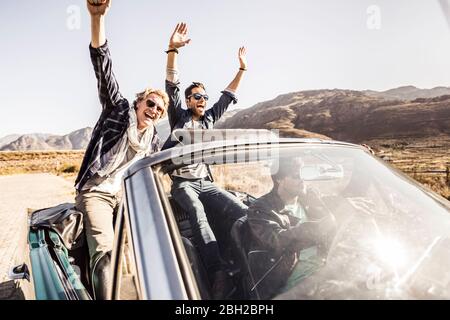 Felici gli amici in auto convertibile in viaggio Foto Stock