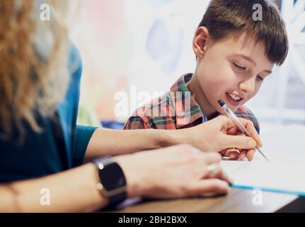 Madre che compila il modulo per suo figlio alla pratica medica Foto Stock