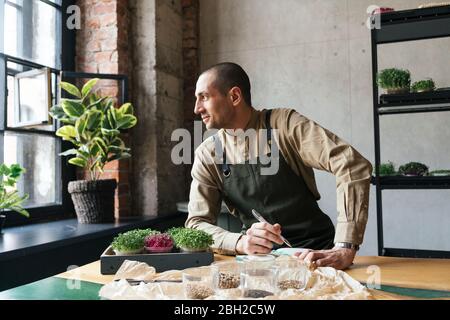 Uomo che pianta micrograni e prendendo note Foto Stock