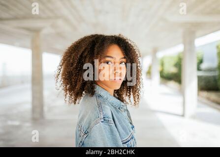 Ritratto di giovane donna sorridente che le tira i capelli in un parcheggio Foto Stock