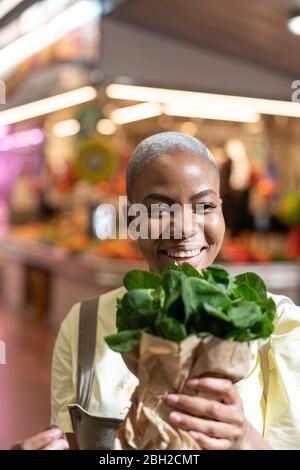 Ritratto di donna felice che tiene la borsa di carta in una sala mercato Foto Stock