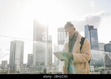 Uomo elegante sulla terrazza di osservazione con tablet, Francoforte, Germania Foto Stock