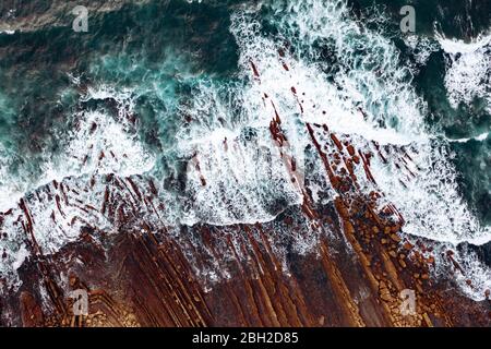 Spagna, Biscaglia, Bilbao, Vista aerea delle onde oceaniche che si infrangono contro la costa rocciosa Foto Stock