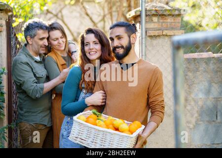 Amici felici che tengono un cestino con limoni e arance Foto Stock