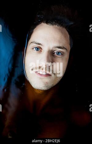 Ritratto di giovane uomo con occhi blu in acqua Foto Stock