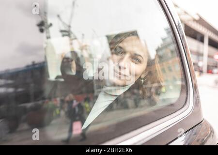 Donna sul retro di un taxi che guarda fuori dalla finestra, Londra, Regno Unito Foto Stock