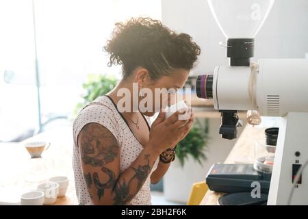 Donna che lavora in una maestria del caffè che odora il prodotto Foto Stock