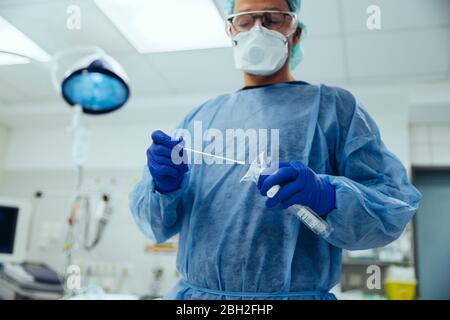 Medico emergenico che mette un tampone in una provetta in ospedale Foto Stock