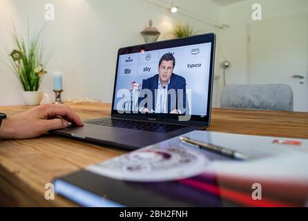 Warendorf, Germania. 23 aprile 2020. Un uomo guarda il monitor del suo laptop, sul quale Christian Seifert, CEO e portavoce del Comitato Esecutivo della Lega di Calcio tedesca (DFL), può essere visto durante una videoconferenza stampa dal vivo dopo l'incontro generale del DFL sulle conseguenze della pandemia di Corona. Credit: Guido Kirchner/dpa/Alamy Live News Foto Stock