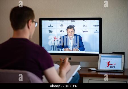 Warendorf, Germania. 23 aprile 2020. Un uomo guarda il monitor del suo computer, sul quale Christian Seifert, CEO e portavoce del Comitato Esecutivo della Lega di Calcio tedesca (DFL), può essere visto durante una videoconferenza stampa dal vivo dopo l'incontro generale del DFL sulle conseguenze della pandemia di Corona. Credit: Guido Kirchner/dpa/Alamy Live News Foto Stock