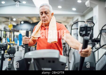 Uomo anziano che pratica allo stepper in palestra Foto Stock