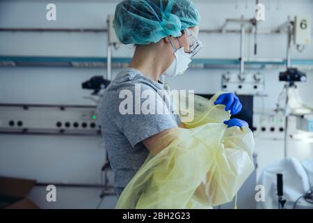 Medico che decollo dispositivi di protezione individuale in ospedale Foto Stock