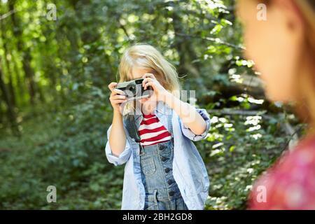 Ragazza che fa foto in foresta con una vecchia fotocamera Foto Stock