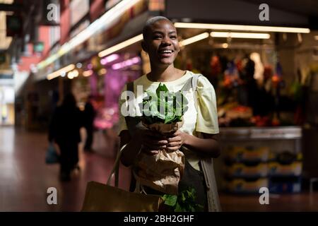 Ritratto di donna felice che tiene la borsa di carta in una sala mercato Foto Stock